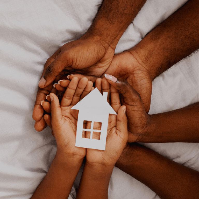 Hands holding a cutout image of a house.